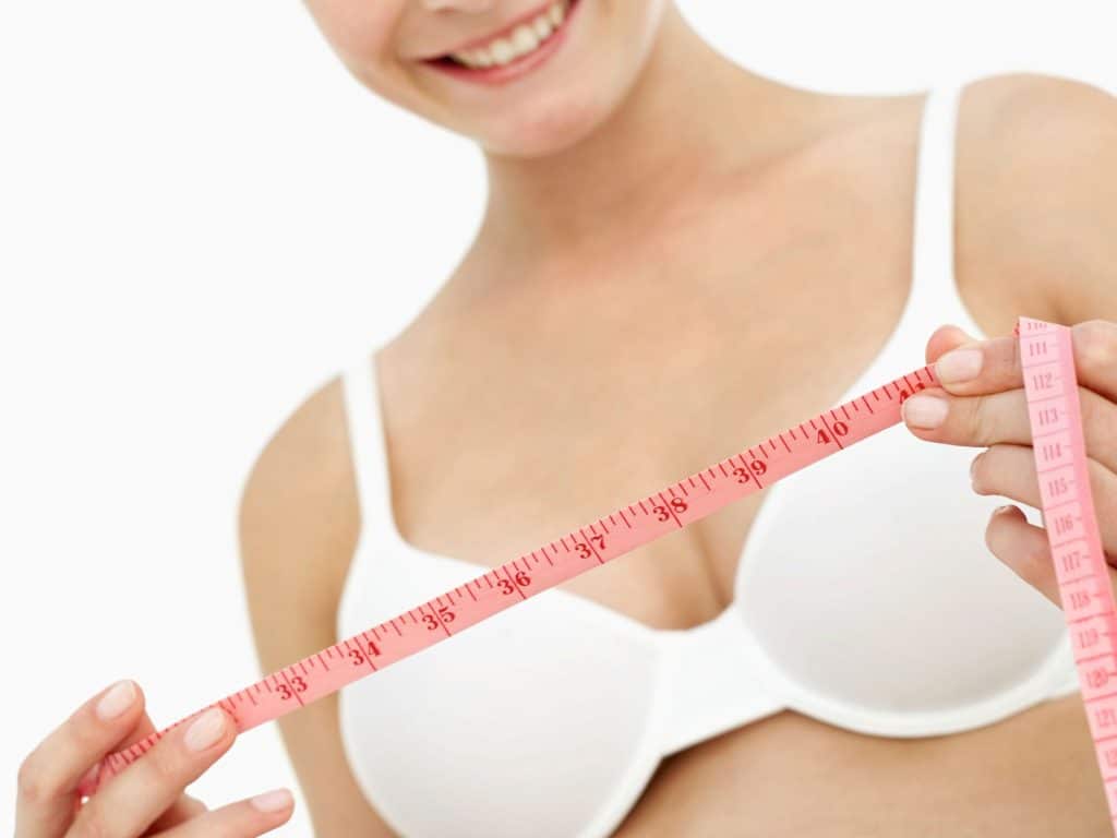 woman holding measuring tape to measure her bra size